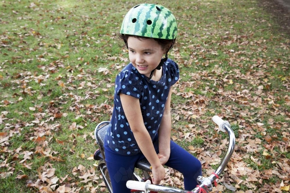Young girl wearing helmet and sitting on bike - Australian Stock Image