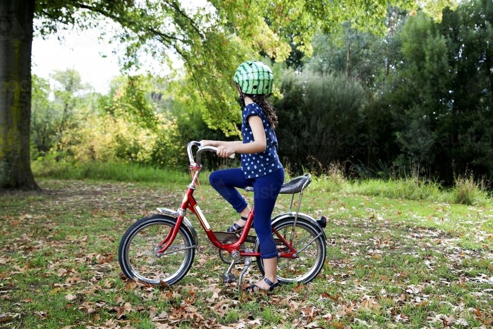 Young girl wearing helmet riding bike - Australian Stock Image
