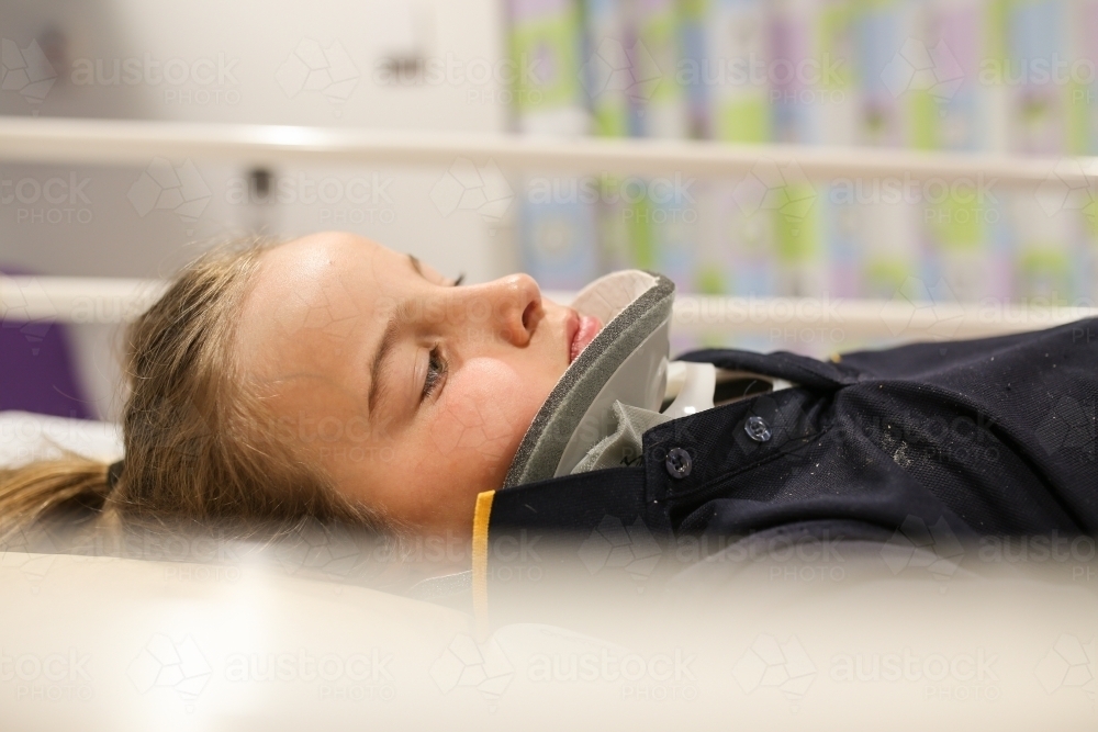 Young girl wearing neck brace in hospital bed - Australian Stock Image