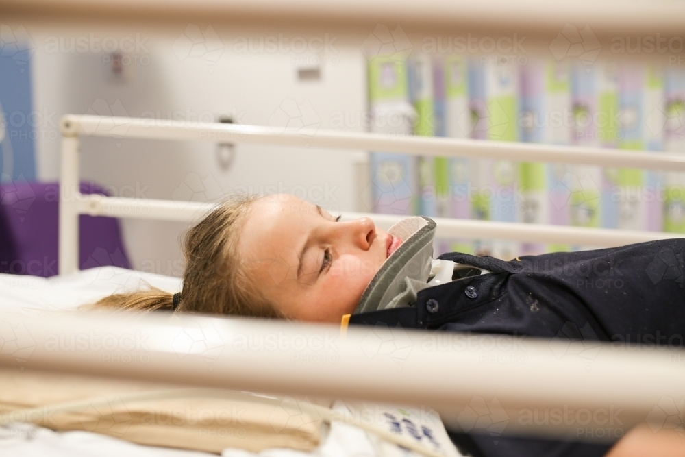 Young girl wearing neck brace in hospital bed - Australian Stock Image