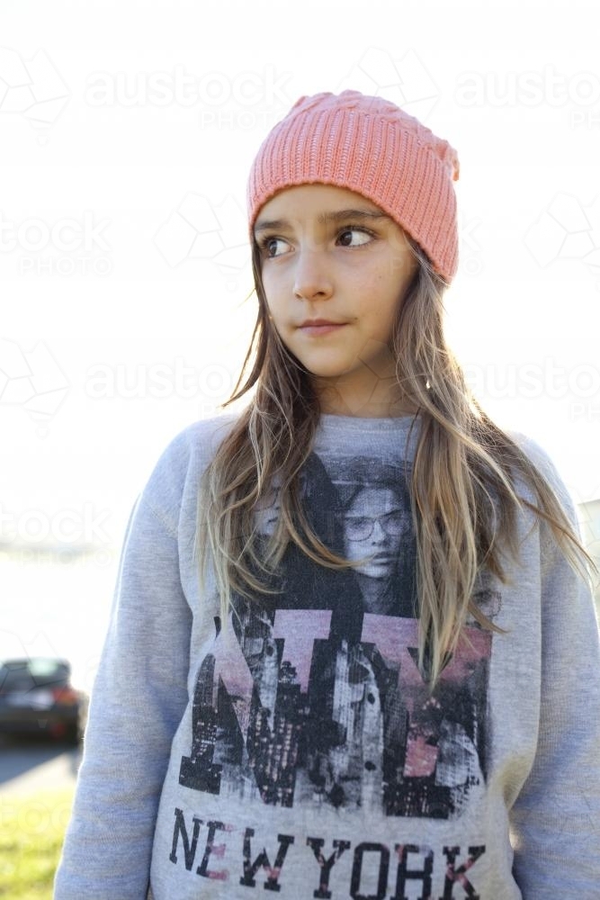 Young girl with beanie on looking away from camera in afternoon light - Australian Stock Image