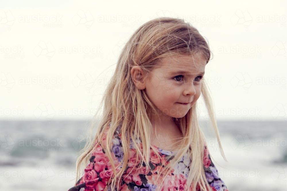 Young girl with blonde hair on beach looking away - Australian Stock Image