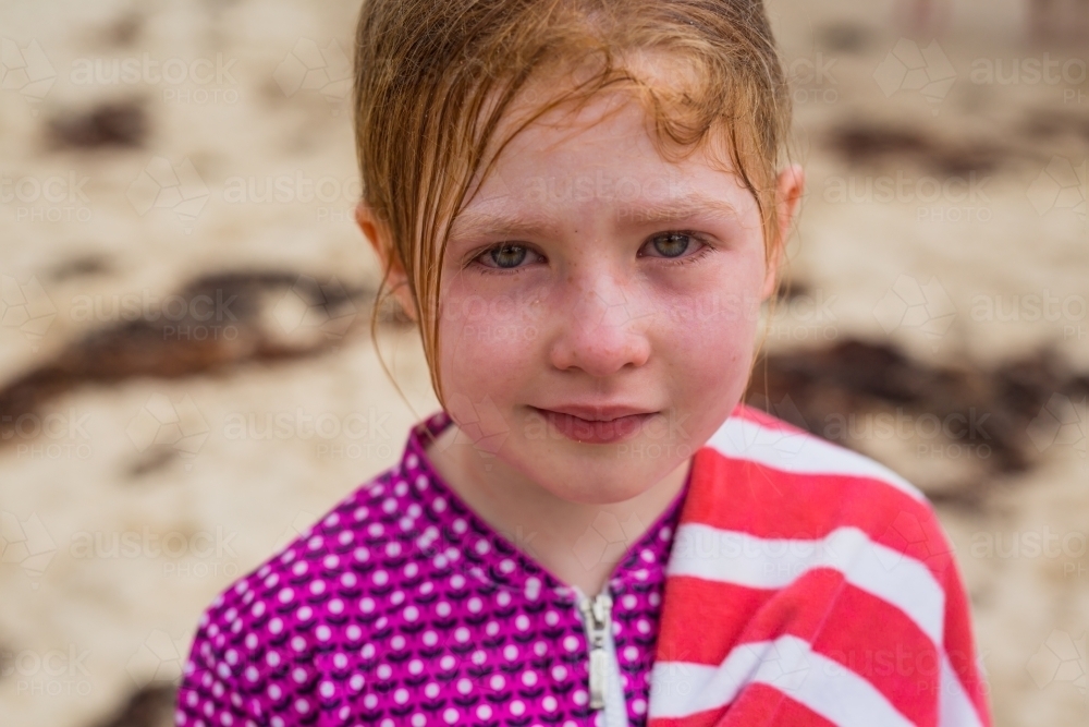 young girl with bloodshot eyes and messy hair after being dumped by a wave - Australian Stock Image
