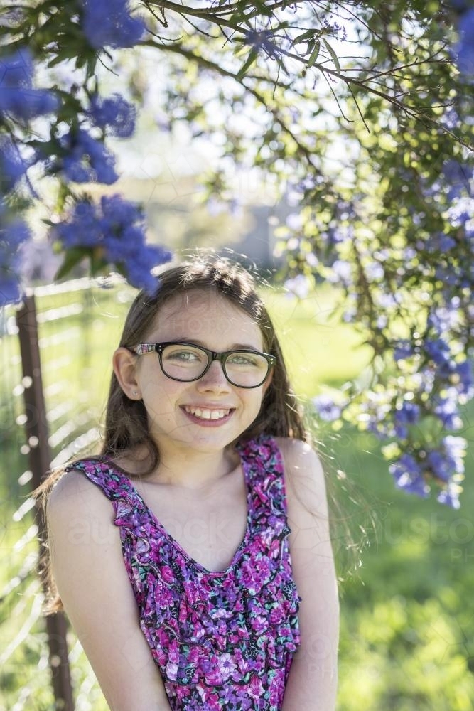 Young girl with glasses under a jacaranda tree - Australian Stock Image