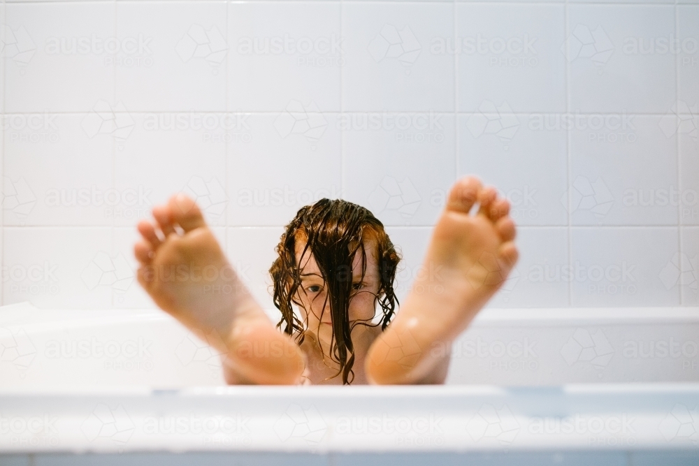 Young girl with her hair over her head sitting in a bath - Australian Stock Image