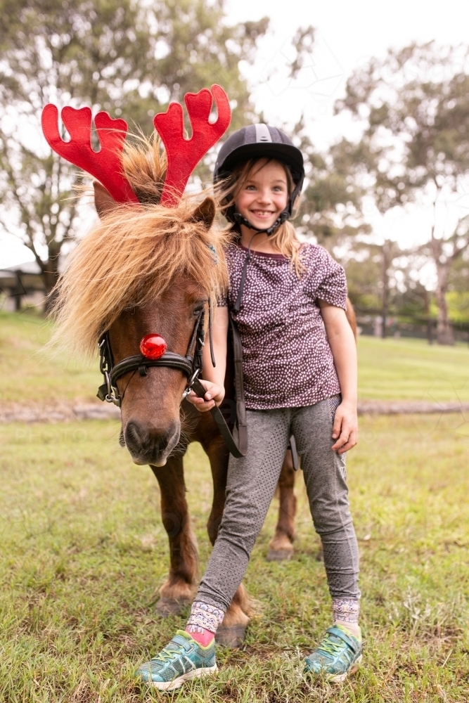 Young girl with horse dressed as reindeer for christmas - Australian Stock Image