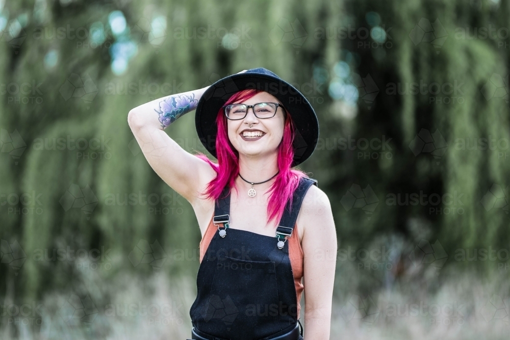 Young girl with pink hair laughing holding hat - Australian Stock Image