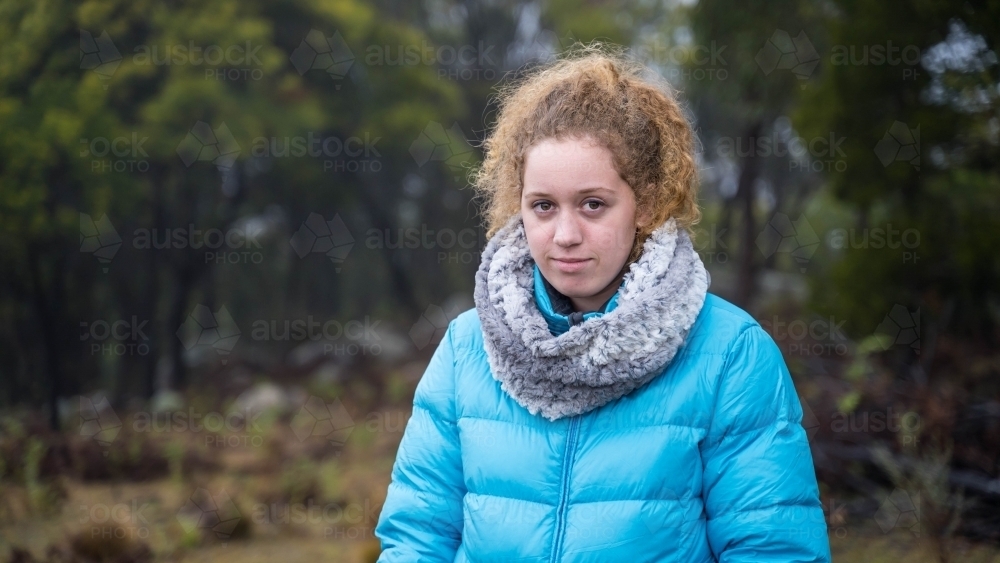 Young girl with red hair and blue jacket looking at camera - Australian Stock Image