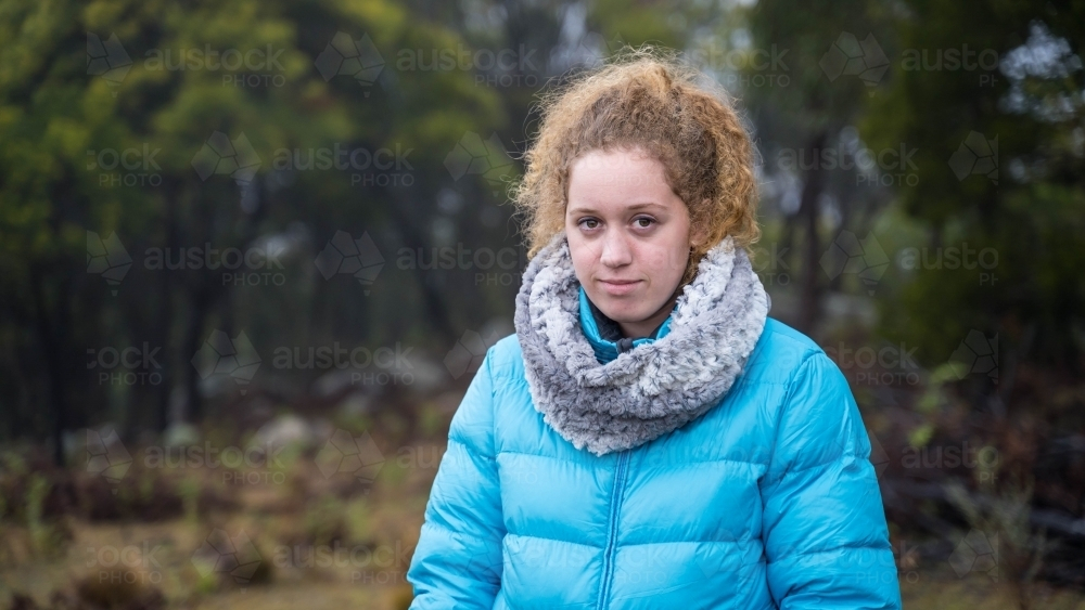 Young girl with red hair and blue jacket outdoors - Australian Stock Image
