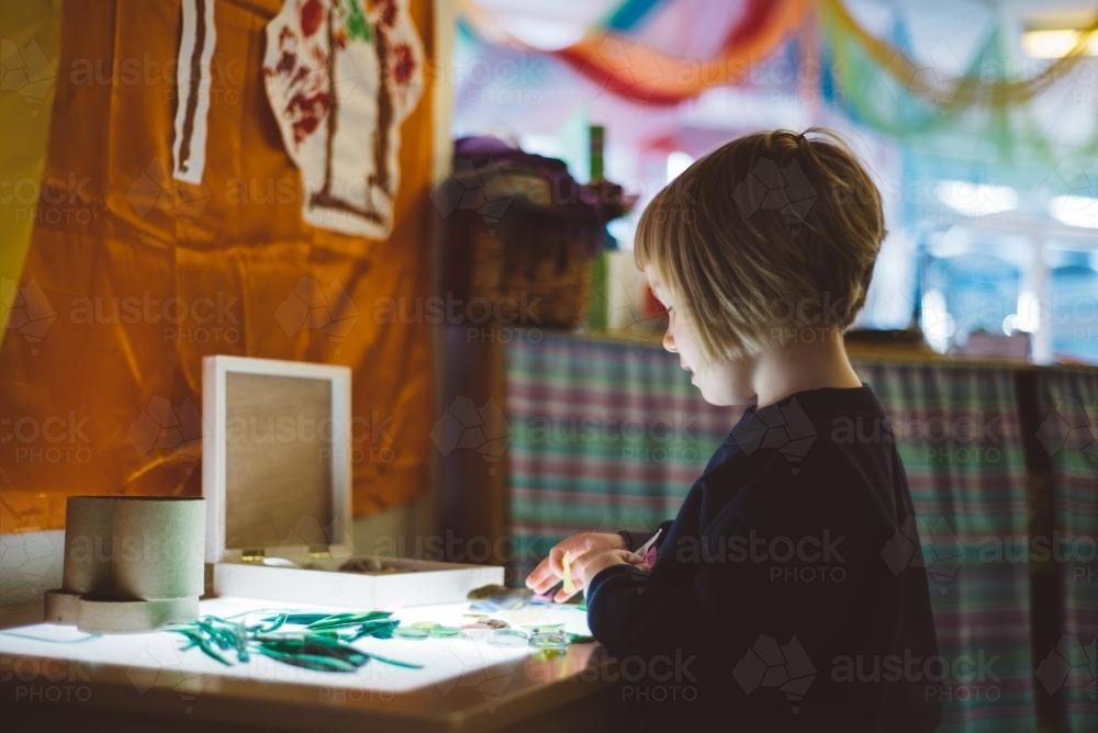 Young girl with short hair at kindergarten doing craft - Australian Stock Image
