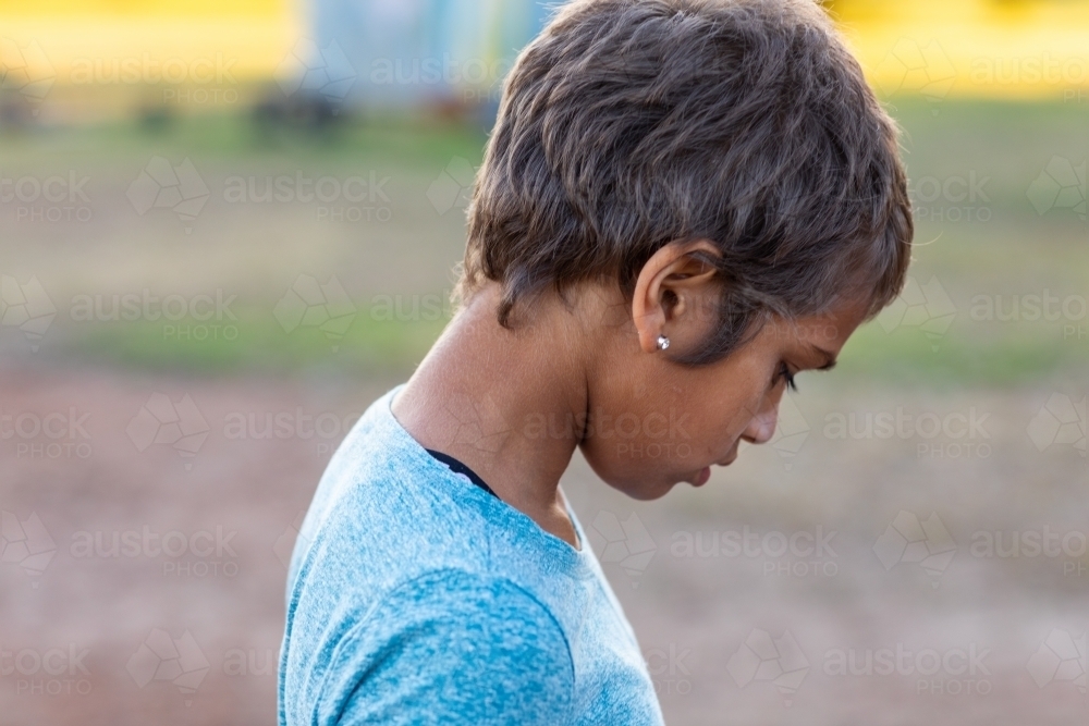young girl with short hair hanging her head down in profile - Australian Stock Image