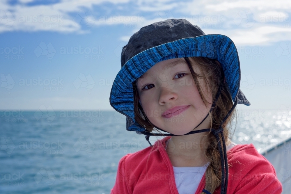 Young girl with sunhat on boat with ocean in the background - Australian Stock Image