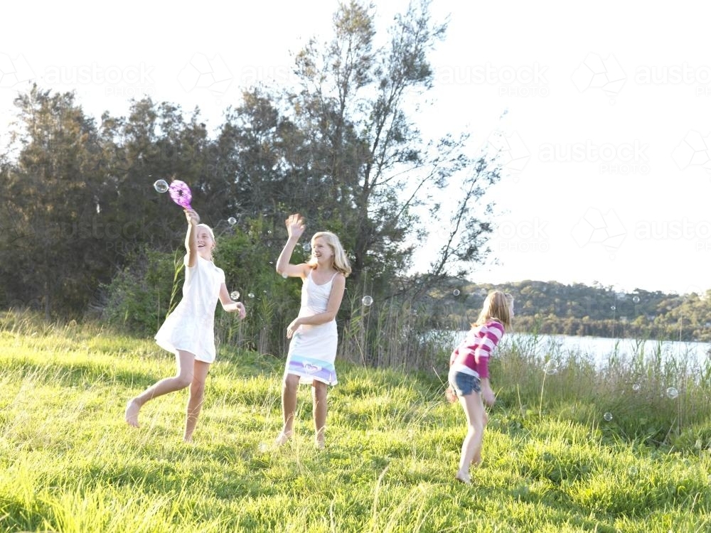 Young girls chasing bubbles outside - Australian Stock Image