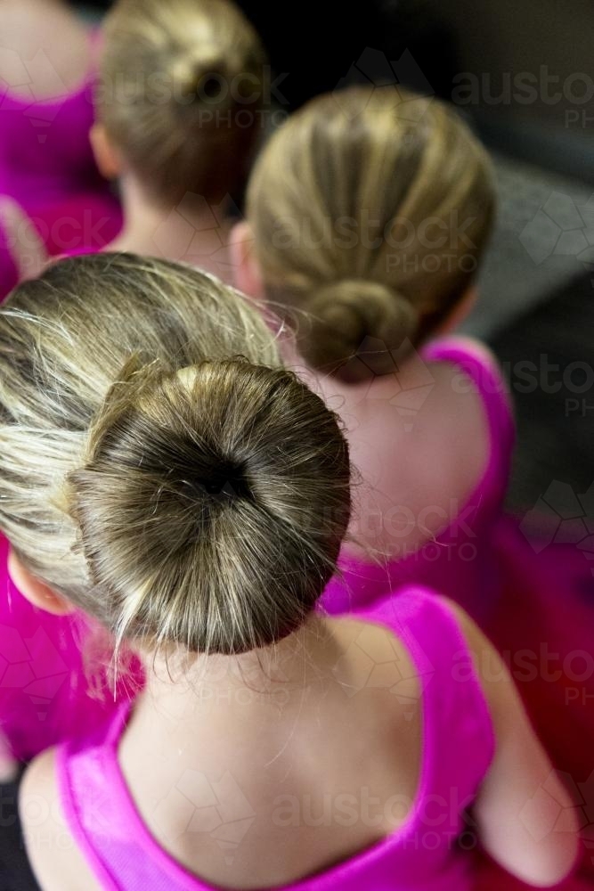 Young girls dressed in pink and wearing buns ready to perform at a ballet concert - Australian Stock Image
