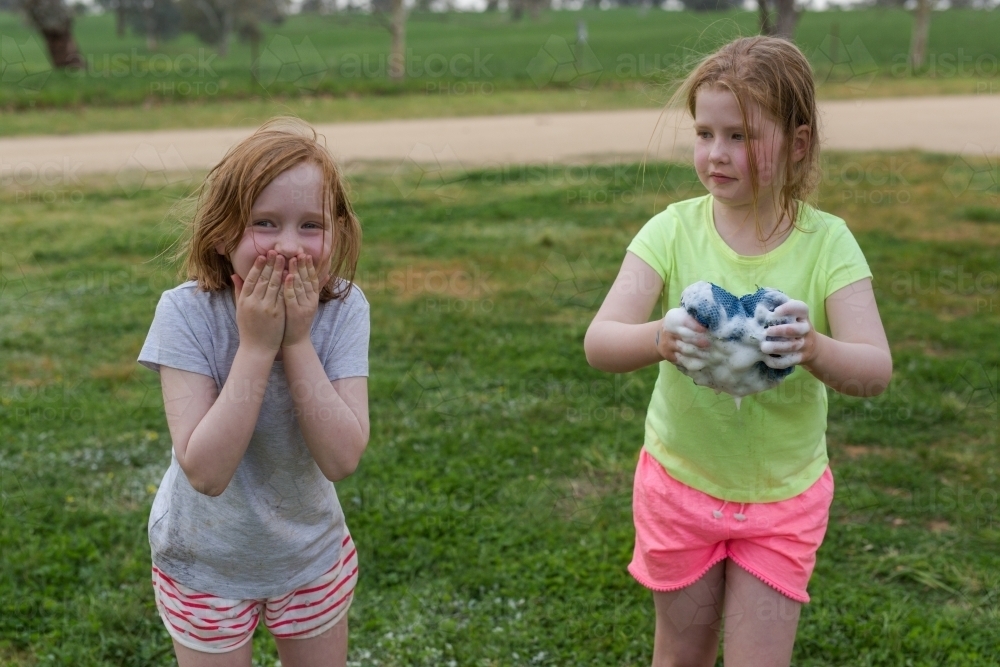 Young girls laughing and holding a soapy sponge - Australian Stock Image
