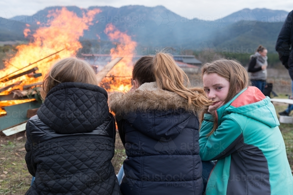 young girls sitting by bonfire - Australian Stock Image