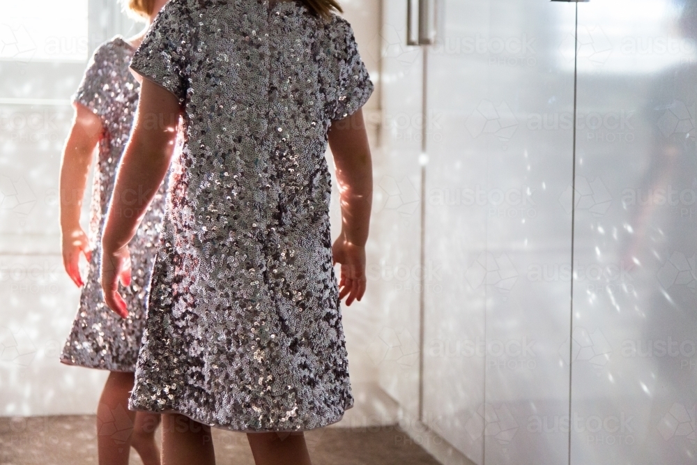 Young girls wearing sparkly dresses playing with the reflected light - Australian Stock Image
