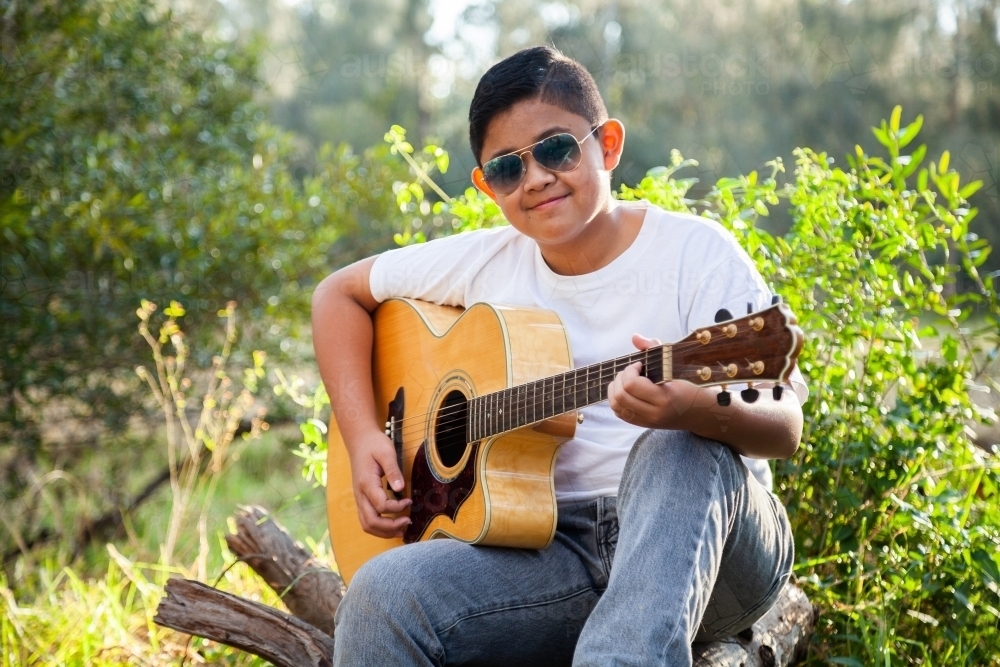 Young guitarist playing musical instrument in the bush - Australian Stock Image