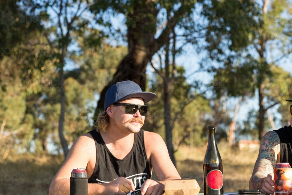 Young guy wearing sunnies with cap, can and bottle - Australian Stock Image