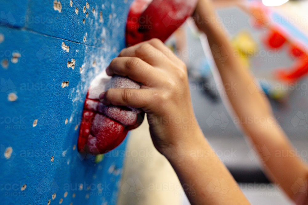Young hand holding on the climbing holds of the bouldering wall - Australian Stock Image