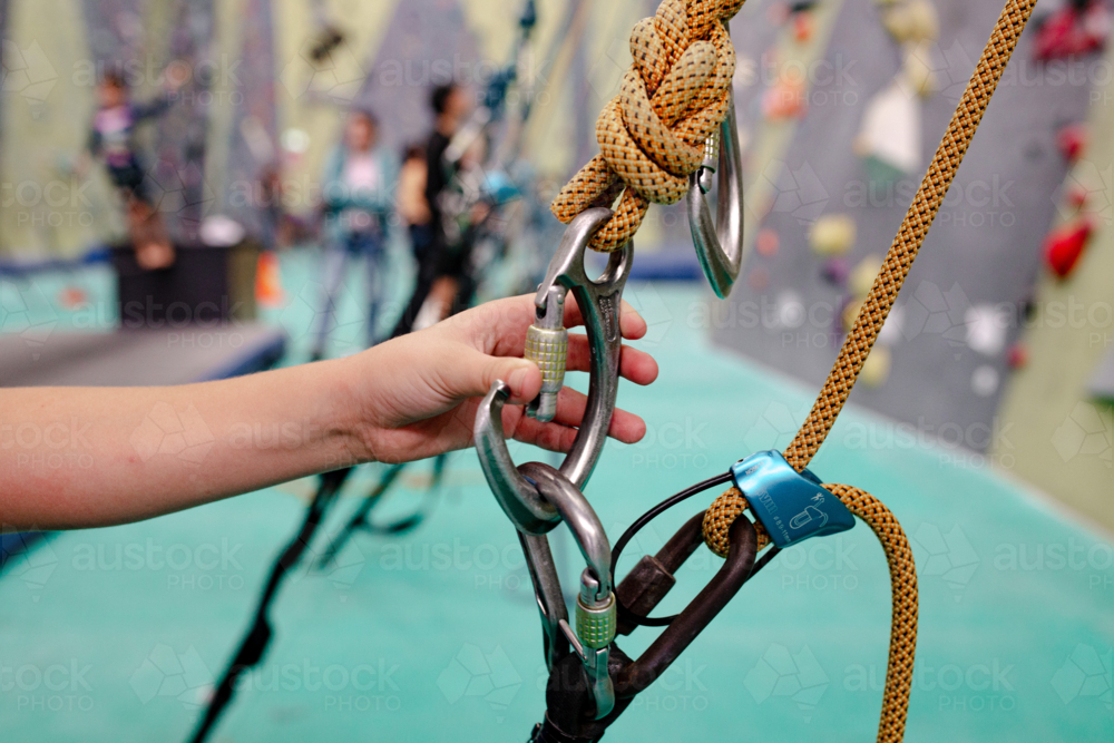 Young hand holding the carabiner in indoor rock-climbing gym - Australian Stock Image
