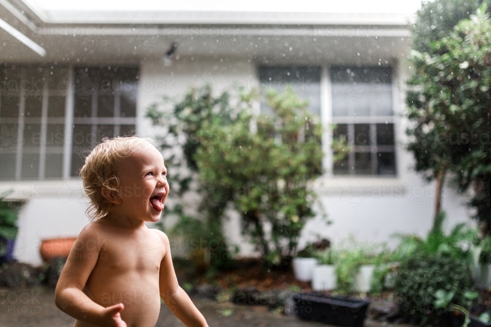 Young happy girl playing in the rain - Australian Stock Image