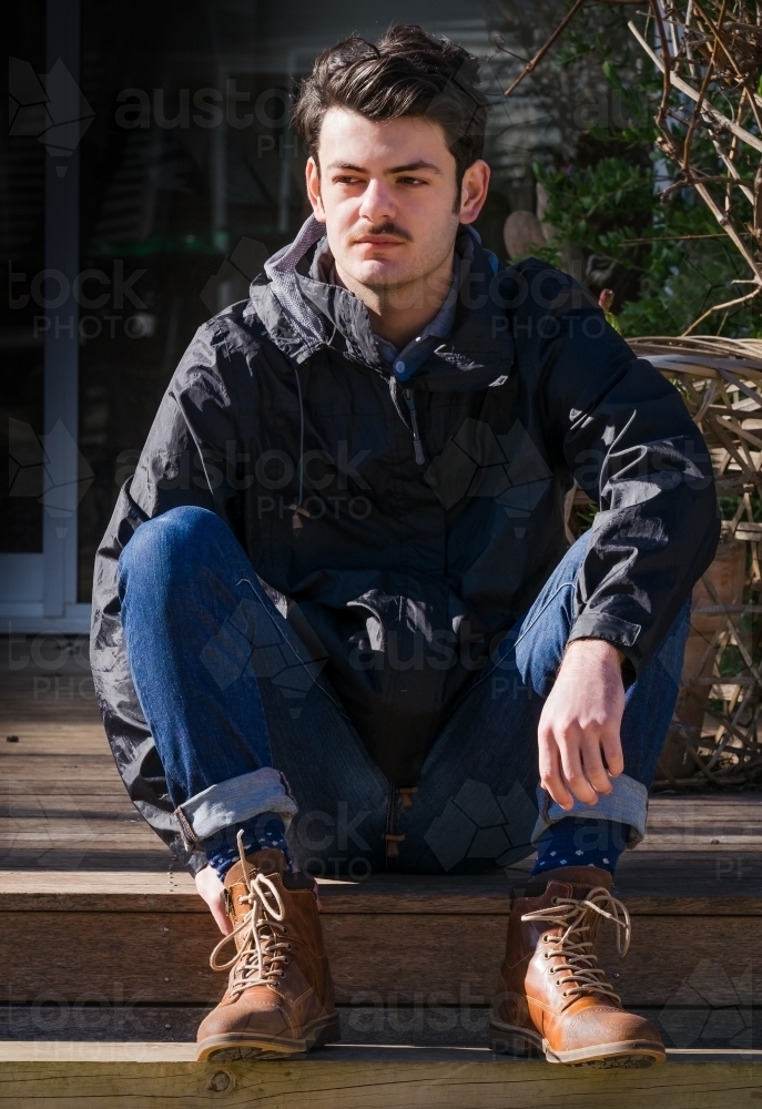 Image of Young hip man sitting in the morning sun. - Austockphoto