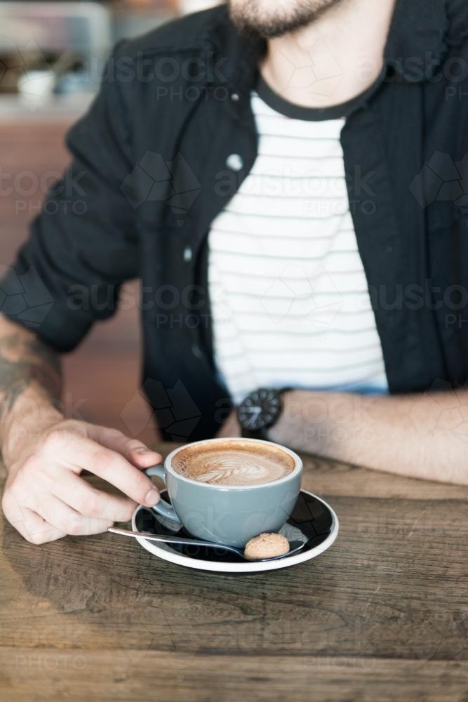Young hipster man drinking coffee in a modern cafe - Australian Stock Image