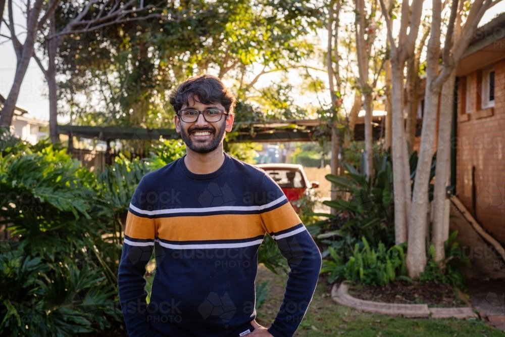 Young Indian man wearing glasses standing outdoors smiling - Australian Stock Image