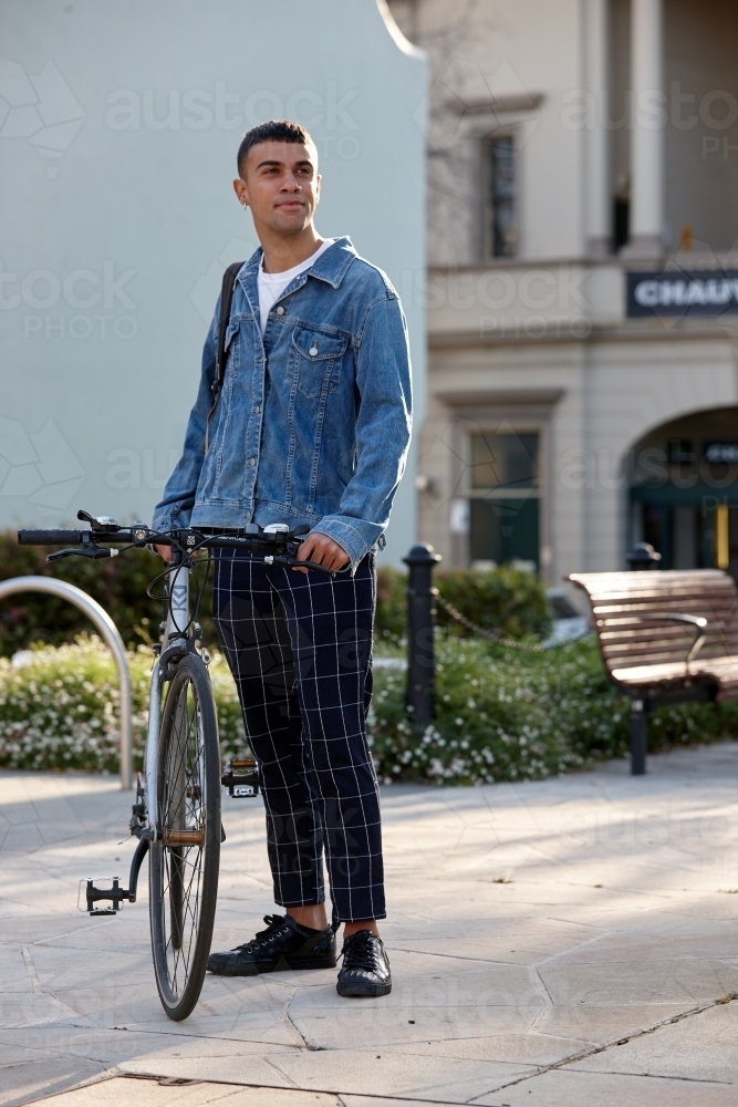 Young Indigenous Australian man at park with bicycle - Australian Stock Image