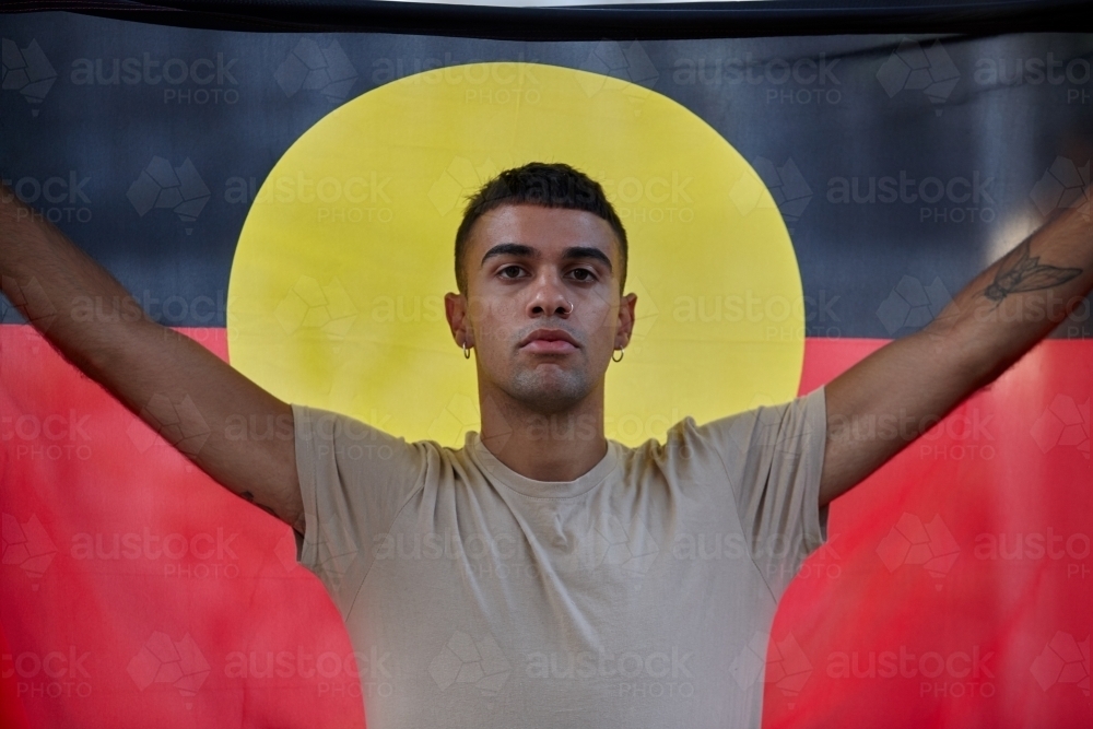 Young Indigenous Australian man holding Aboriginal flag - Australian Stock Image