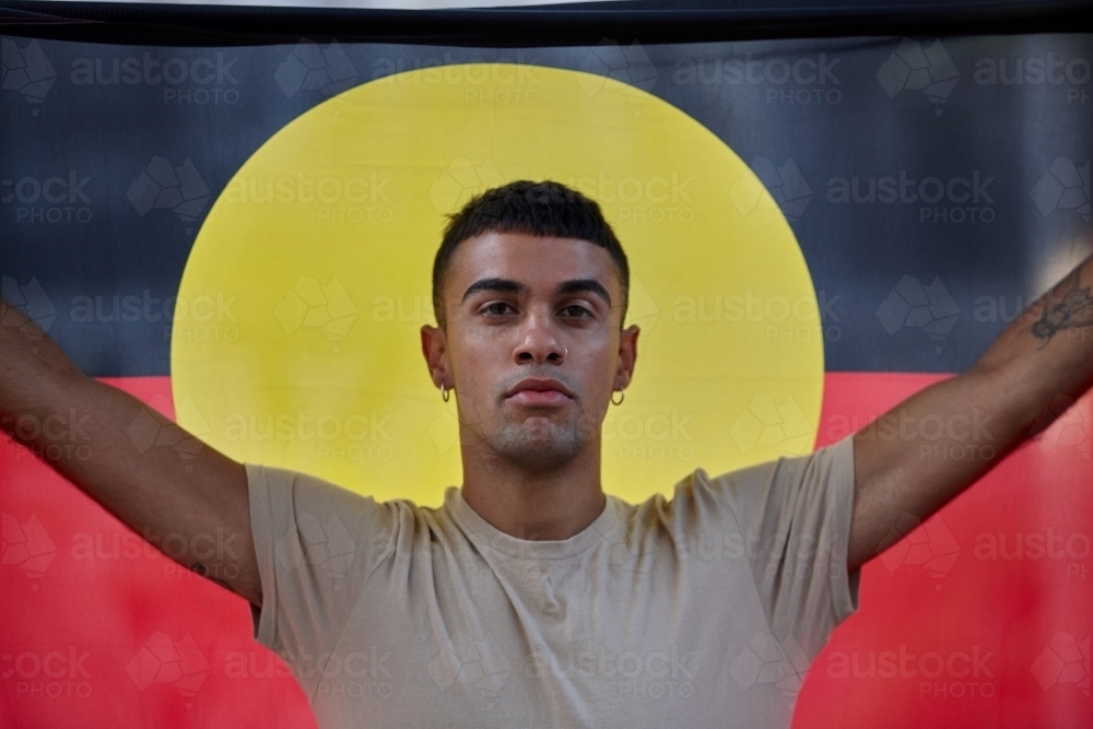 Young Indigenous Australian man holding Aboriginal flag - Australian Stock Image