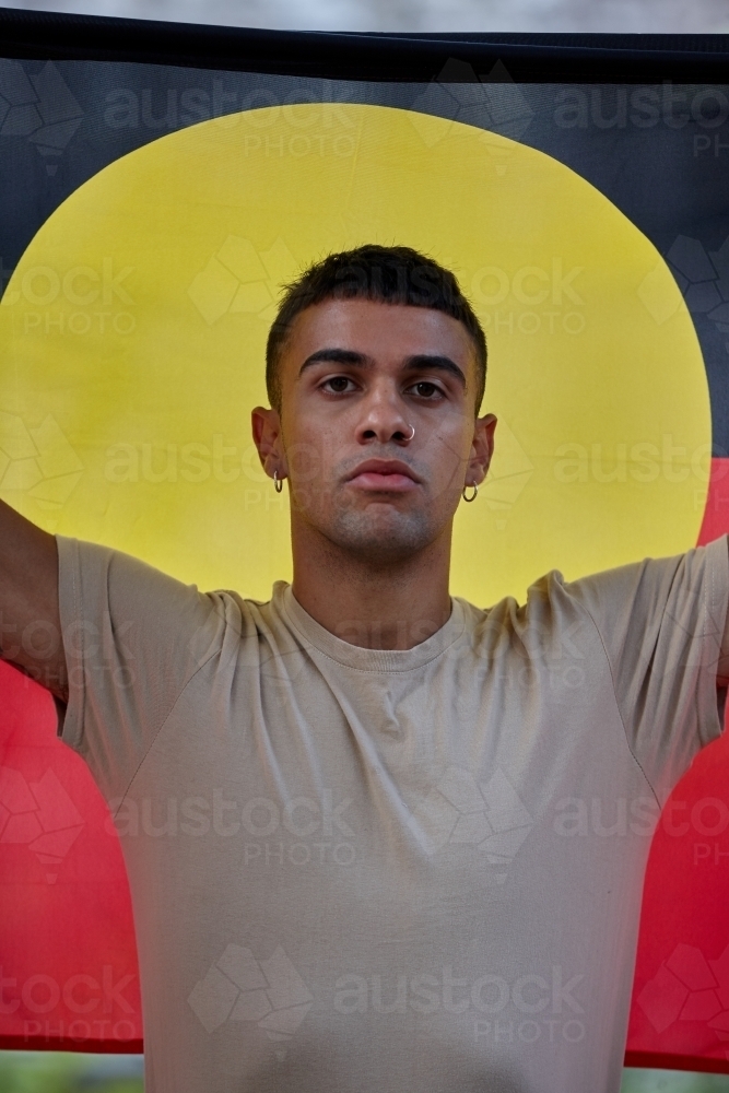 Young Indigenous Australian man holding Aboriginal flag - Australian Stock Image