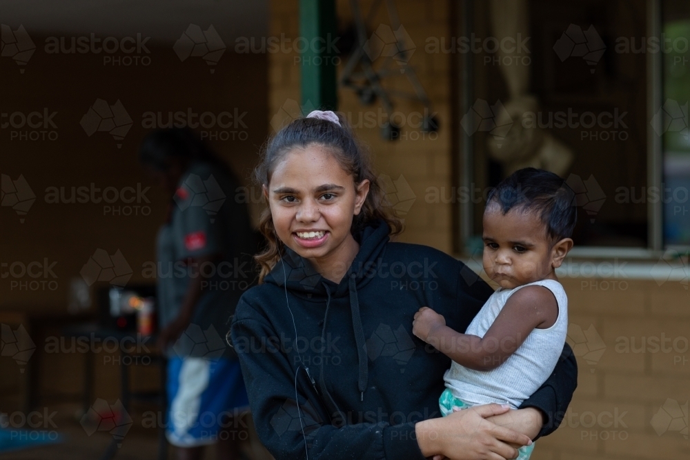 Young indigenous girl with baby on hip - Australian Stock Image