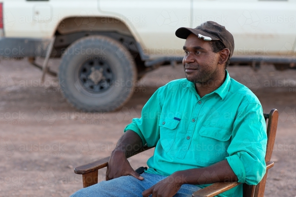 Young indigenous man relaxing in chair outdoors - Australian Stock Image