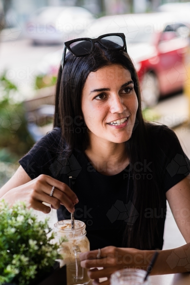 young indigenous woman having a coffee in a cafe - Australian Stock Image