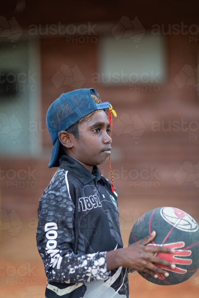 young kid holding basketball outside his home - Australian Stock Image