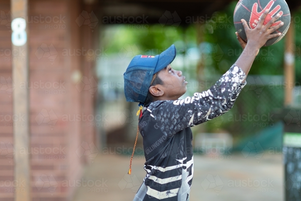 young lad shooting basketball outside his home - Australian Stock Image