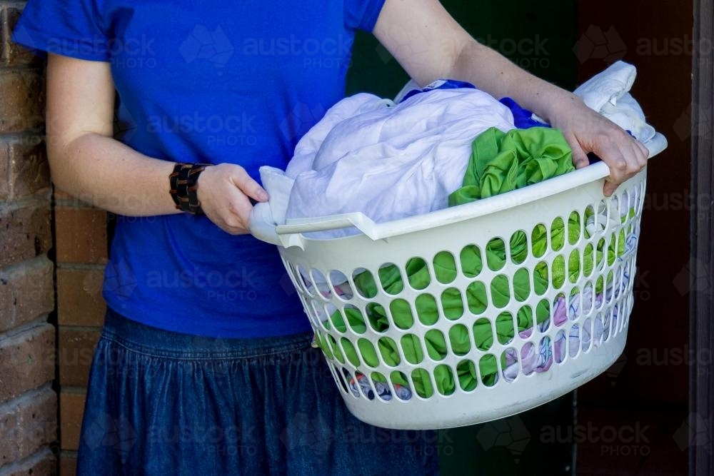 Image of Young lady holding a basket of wet washing Austockphoto