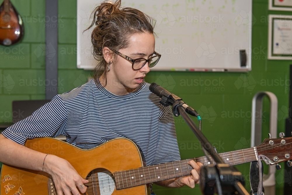 Young lady playing guitar and singing - Australian Stock Image