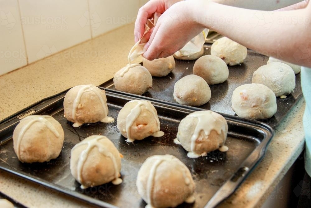 Image of Young lady putting crosses on the hot cross buns Austockphoto