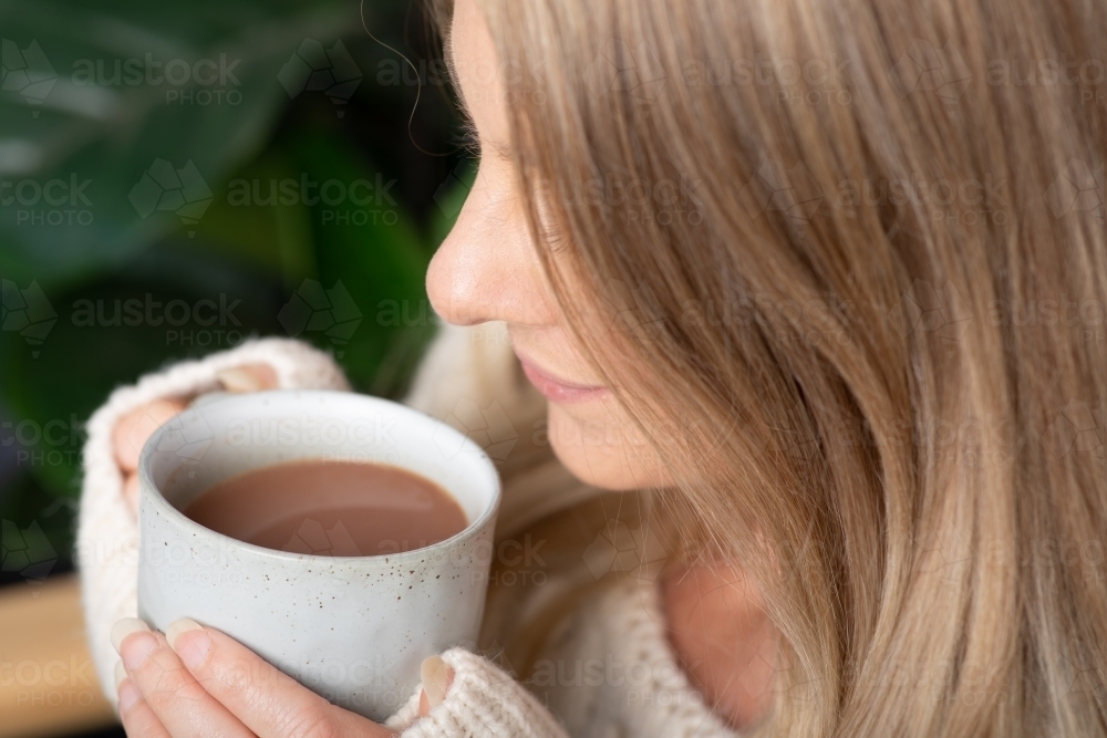 Young lady relaxing drinking hot chocolate or coffee on a cold winters day - Australian Stock Image