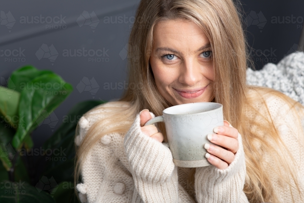 Young lady relaxing drinking hot chocolate or coffee on a cold winters day - Australian Stock Image