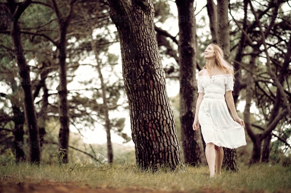 Young lady walking in the woods in a white dress - Australian Stock Image
