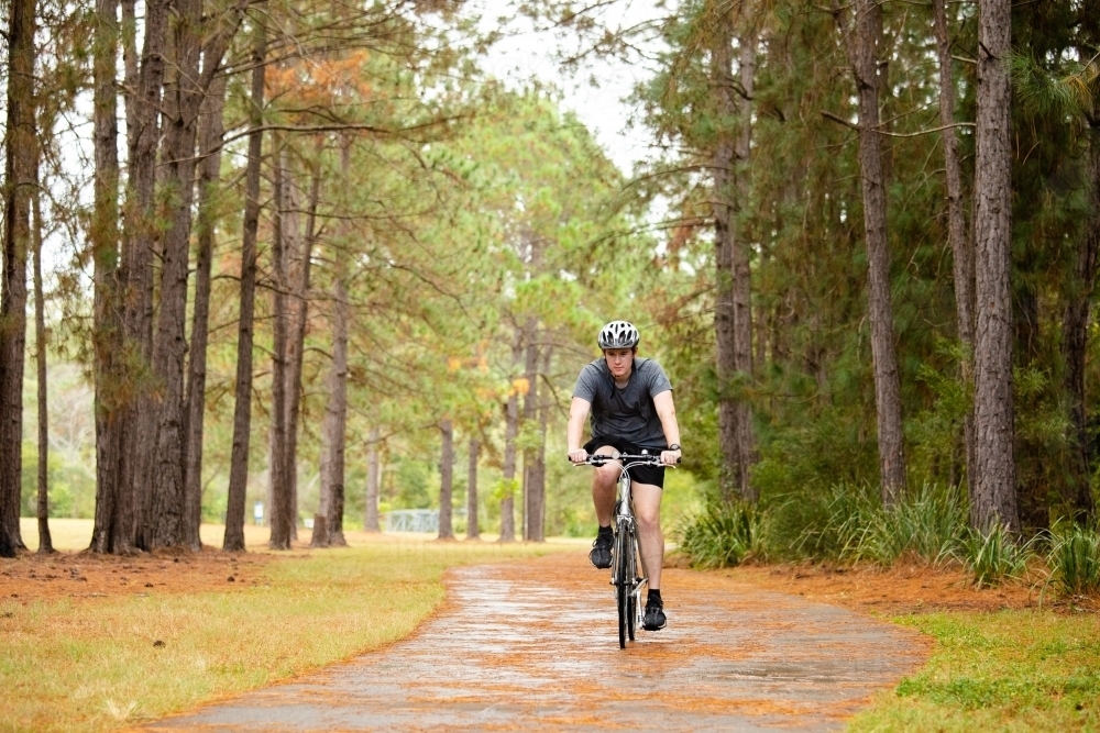 Young male cycling along a parkland bike path - Australian Stock Image