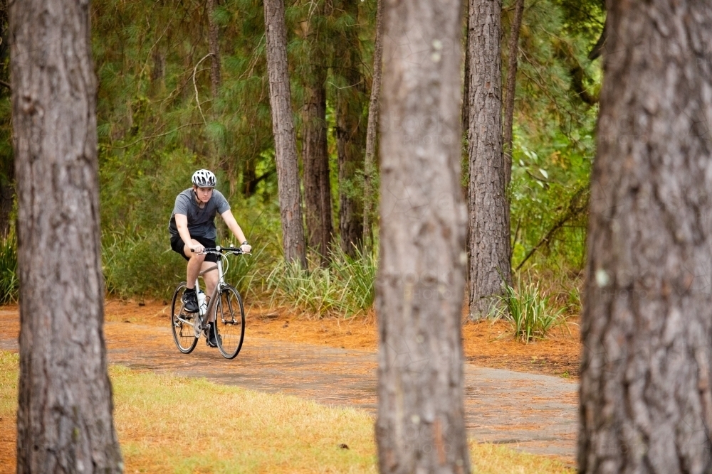 Young male cycling along a parkland bike path - Australian Stock Image