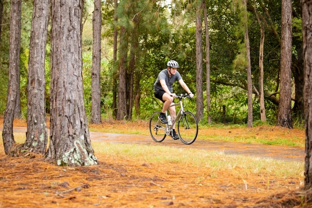 Young male cycling along a parkland bike path : Austockphoto Young male cycling along a parkland bike path - Australian Stock Image