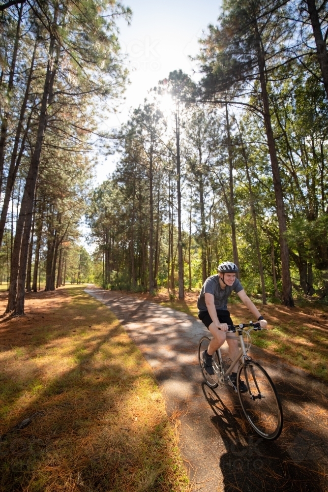 Young male cycling along a parkland bike path - Australian Stock Image