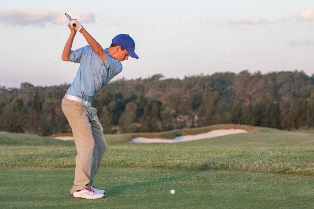 Young male golfer about to play iron shot - Australian Stock Image