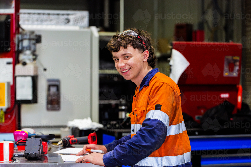 Young male mechanic working at tool bench doing paperwork on vehicle fitout - Australian Stock Image